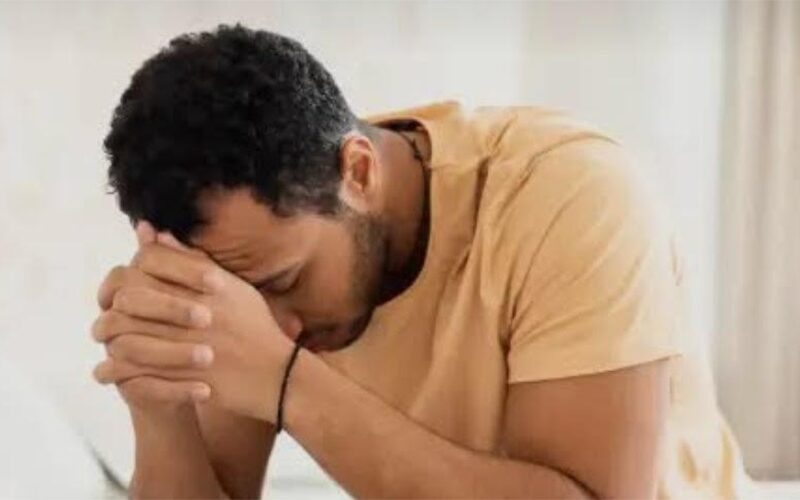 Man sitting at a table with his head in his hands, showing signs of anxiety and overwhelm